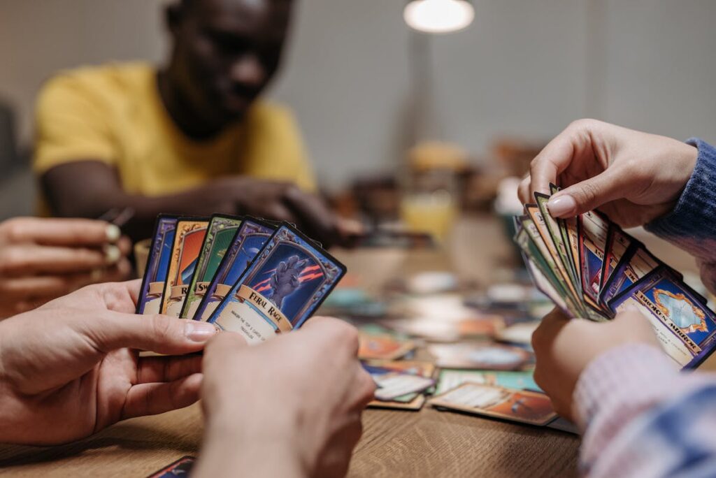 Players at a table, each holding a fan of trading cards