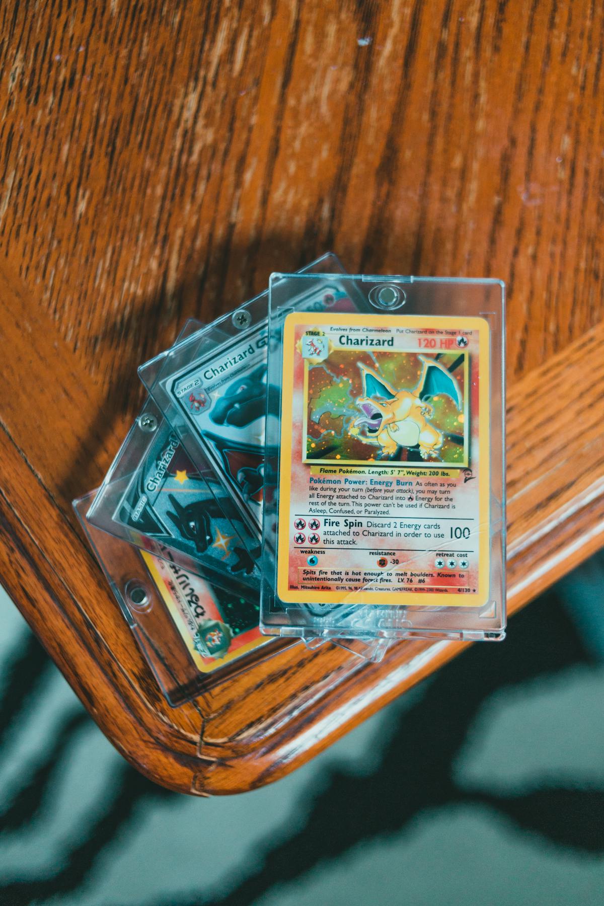 A Charizard card in a clear top-loader on an oak table